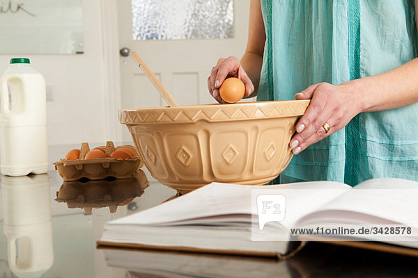 Woman breaking egg into bowl