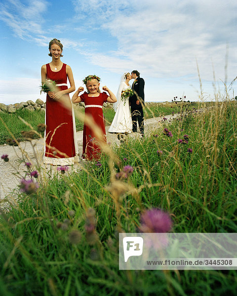 Skandinavien  Schweden  Oland  Brautjungfer und Blumen-Mädchen mit Braut und Bräutigam küssen im Hintergrund