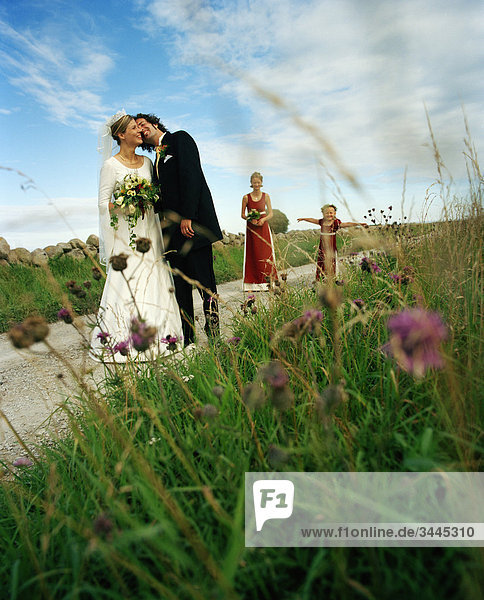 Scandinavia  Sweden  Oland  Bride and groom kissing with bridesmaid and flower girl in background