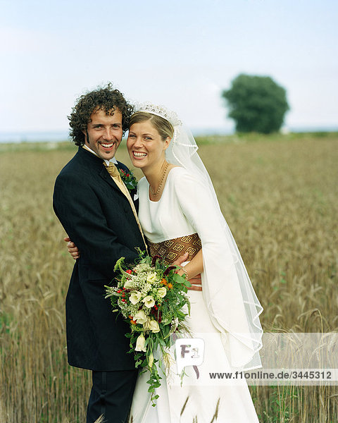 Scandinavia  Sweden  Oland  Bride and groom standing in field  smiling  portrait