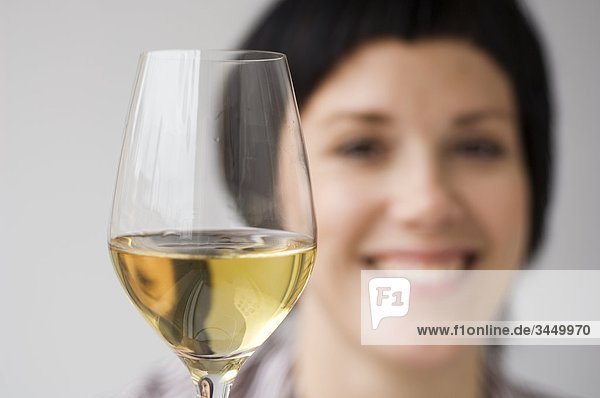 Frau lächelnd mit Glas Wein im Vordergrund  Nahaufnahme