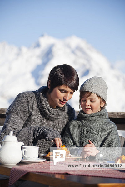 Mutter und Tochter beim Essen auf dem Balkon im Skigebiet
