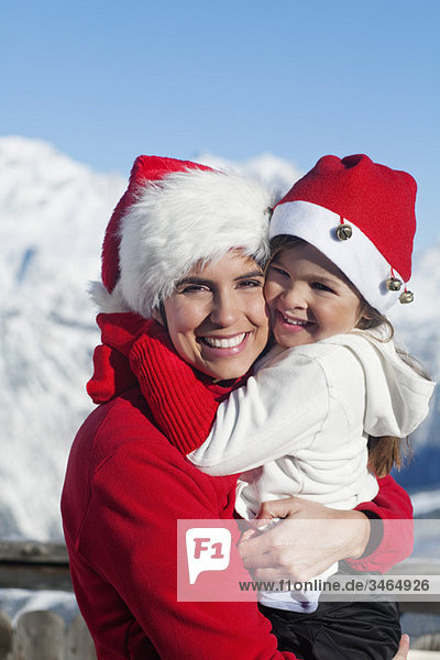Mother and dauhter wearing Santa hats  hugging