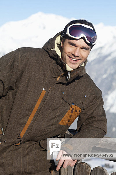 Junger Mann in Skikleidung lächelnd vor der Kamera