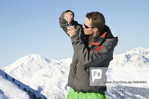 Junger Mann in Skibekleidung beim Fotografieren