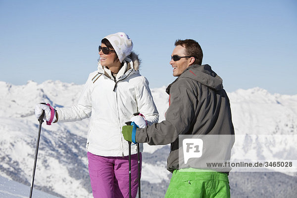 Young couple of skiers looking away