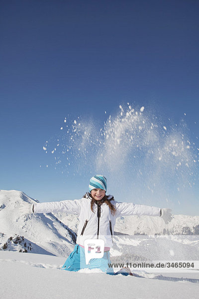 Mädchen in Skikleidung  Schnee in die Luft werfen