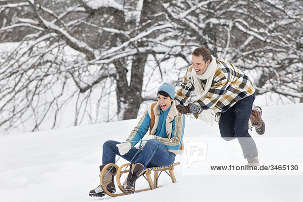 Young man pushing woman on sled