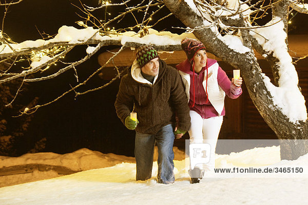 Young couple holding candles  walking in snow by night