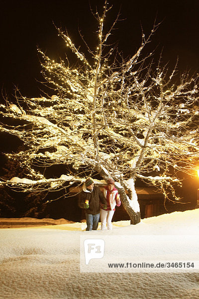 Young couple holding candles  walking in snow by night