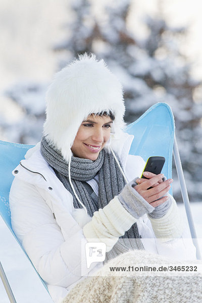 Junge Frau mit Handy im Schnee