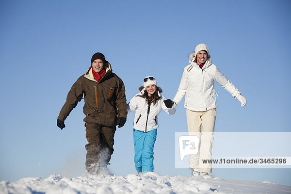 Couple and daughter in ski wear walking in snow