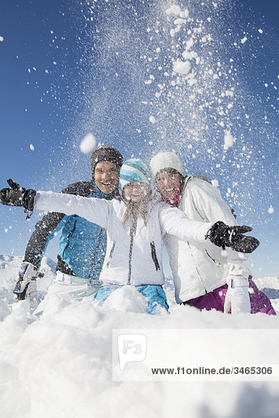 Couple and daughter in ski wear  throwing snow in air