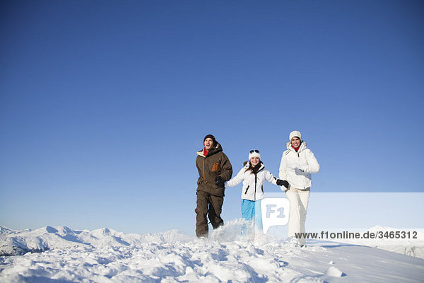 Couple and daughter in ski wear walking in snow