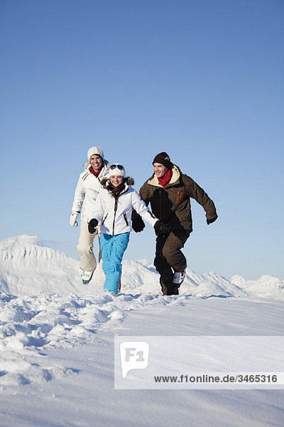 Couple and daughter in ski wear running in snow