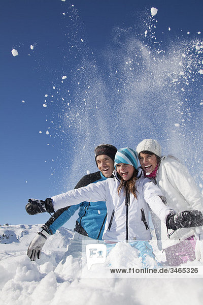 Couple and daughter in ski wear  throwing snow in air