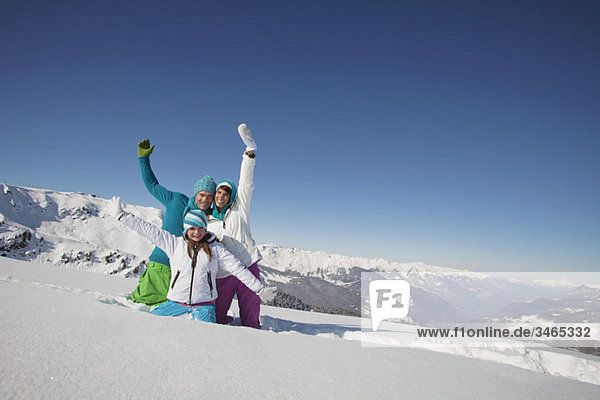 Couple and daughter in ski wear  playing in snow