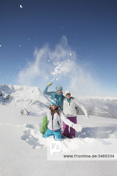 Paar und Tochter in Skibekleidung  Schnee in die Luft werfen