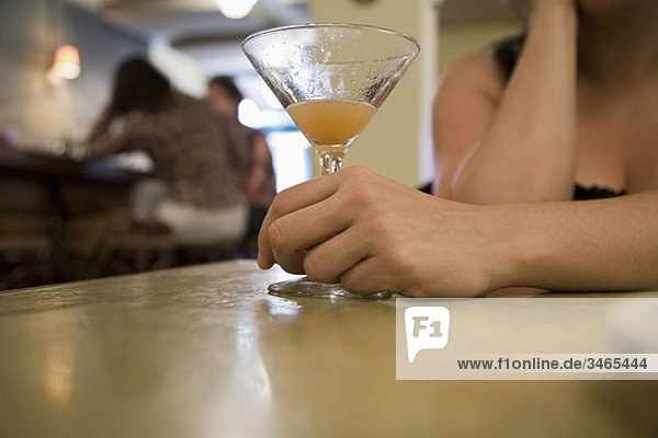 Detail einer Frau  die einen Drink an einer Bar hält.