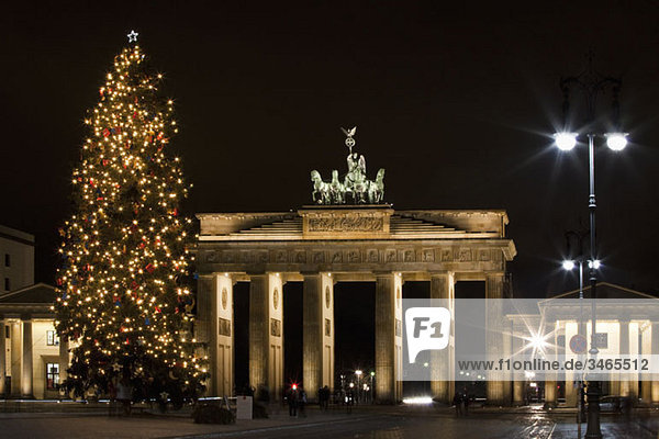 Brandenburg Gate behind a Christmas tree at night  Berlin  Germany