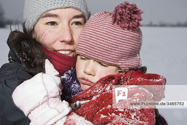 A woman carrying her sleeping daughter  outdoors  portrait