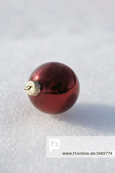 A red Christmas ball ornament on snow