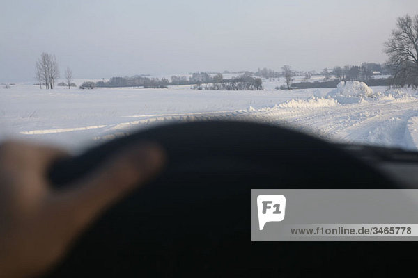View of snow covered country road through car windshield