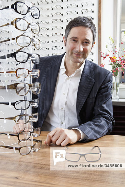A mature man choosing a pair of eyeglasses in an eyewear store