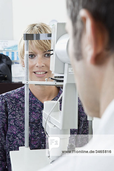 Ein Patient wird von einem Augenarzt mit einem Spaltlampen-Biomikroskop untersucht.