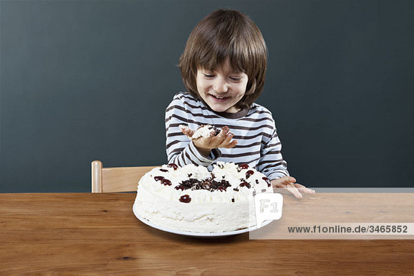 Ein junger lächelnder Junge mit einer Handvoll Kuchen  Studioaufnahme