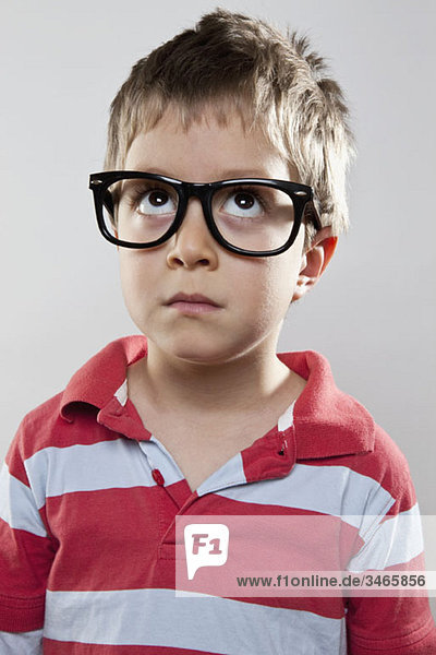 A young boy wearing fake glasses looking up  studio shot