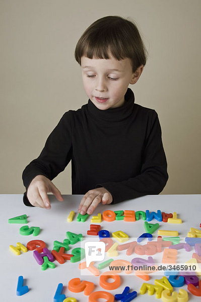 Ein Junge spielt mit Briefmagneten.