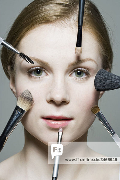 Eine Frau mit verschiedenen Make-up-Pinseln  die Make-up auf ihr Gesicht auftragen.