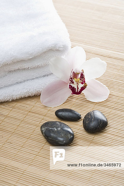 Falthandtücher  Lastone Therapiesteine und eine Orchidee auf einer Tatami-Matte angeordnet