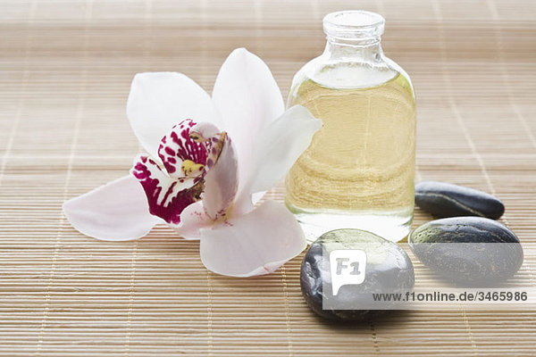 Eine Orchidee  Aromatherapieöl und Lastone Therapiesteine auf einer Tatami-Matte