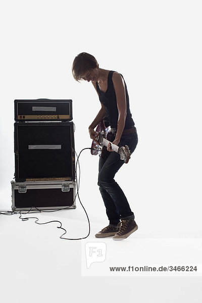 Eine Frau spielt E-Gitarre  Studioaufnahme  weißer Hintergrund  hintergrundbeleuchtet