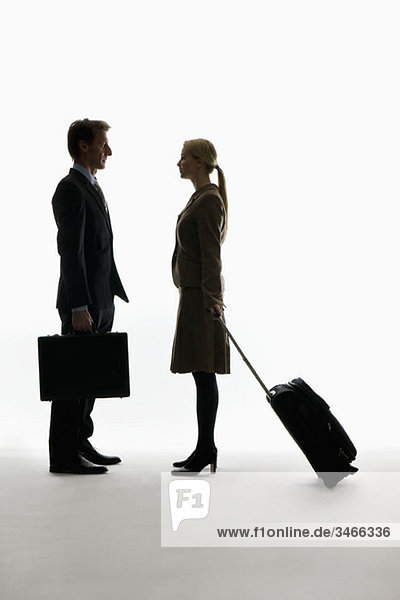 Ein reisender Geschäftsmann und eine Geschäftsfrau  die von Angesicht zu Angesicht stehen.