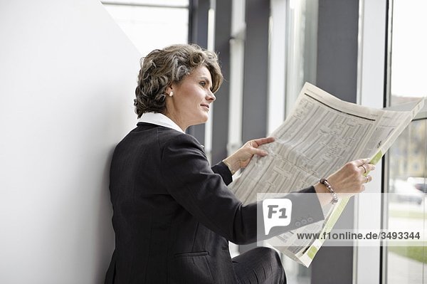 Geschäftsfrau beim Zeitungslesen