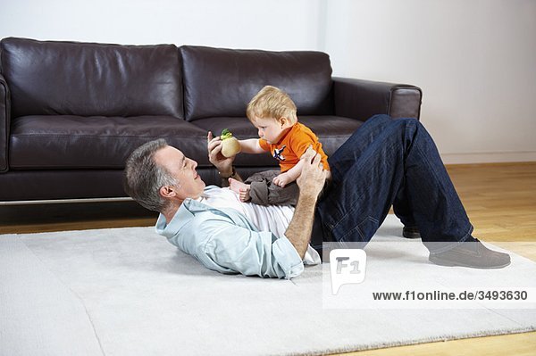 Vater und Baby spielen auf einem Teppich