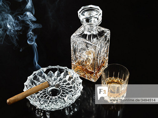 Zigarre im Aschenbecher mit Karaffe und Whiskybecher