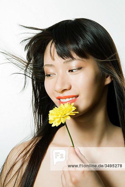 Young woman holding yellow flower