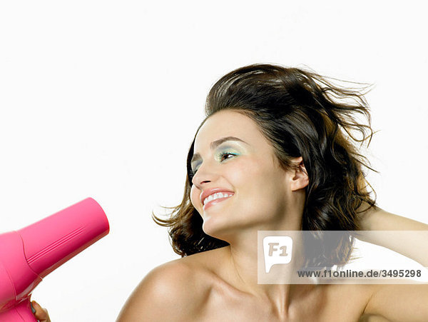 Young woman using hairdryer