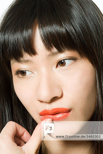Young woman touching lip with thumb