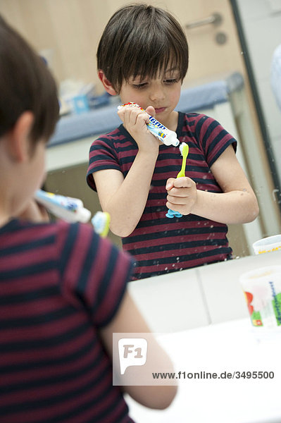 Junge macht sich Zahnpasta auf die Zahnbürste