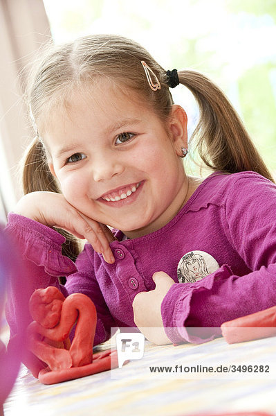 Mädchen an einem Tisch sitzend neben einer Figur aus Knete  Flachwinkelansicht