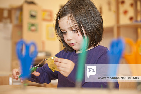 Mädchen schneidet Papier mit einer Schere  Flachwinkelansicht