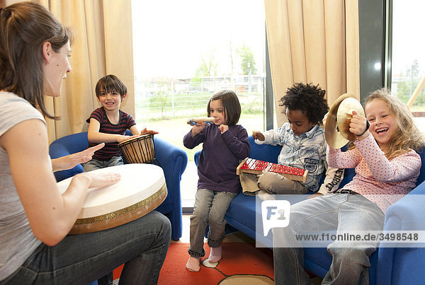 Kindergärtnerin und Kinder musizieren
