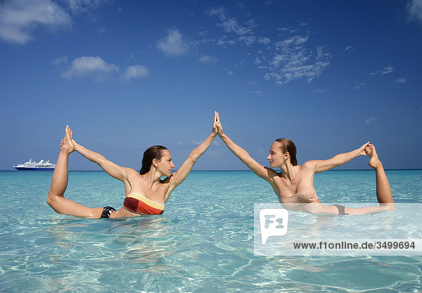 Zwei Frauen machen eine Yogapose im Wasser  Seitenansicht