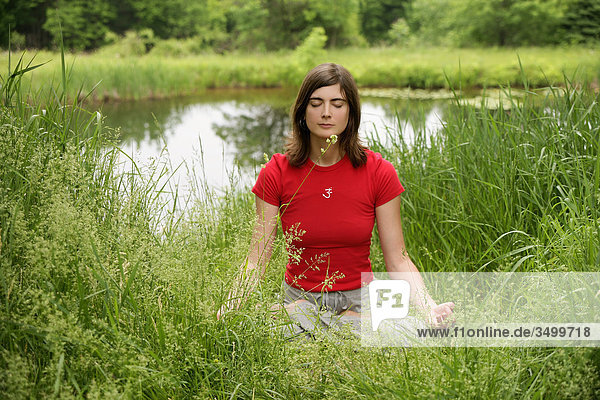 Frau meditiert in der Natur  Frontalansicht