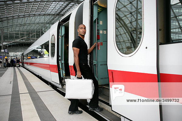 Mann mit Koffer steigt in einen Zug